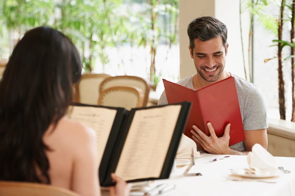 Two individuals reviewing menus at a restaurant table.