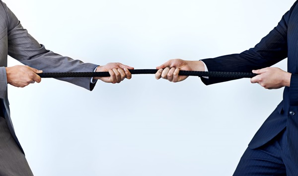 Two people in business attire engaged in a tug of war.